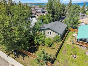 A residential area with houses, a fenced yard, and a view of a body of water. - Cottage Cove, 7Beds, Family Retreat by Sylvan Lake (Sylvan Lake)