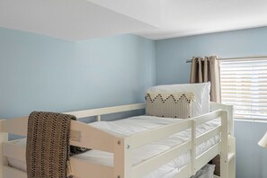 A bunk bed room with a window and curtains.