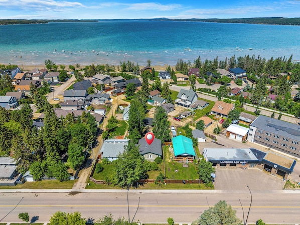 An aerial view of a coastal residential area with houses, a road, and a body of water. - Cottage Cove, 7Beds, Family Retreat by Sylvan Lake (Sylvan Lake)