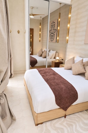 Un dormitorio moderno con una cama grande, un espejo y una mesita de noche.
