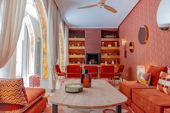 Una habitación con una mesa de comedor, sillas rojas, un sofá y una chimenea.