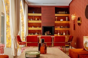 Un comedor con chimenea, sillas rojas y una mesa dispuesta con una vela.