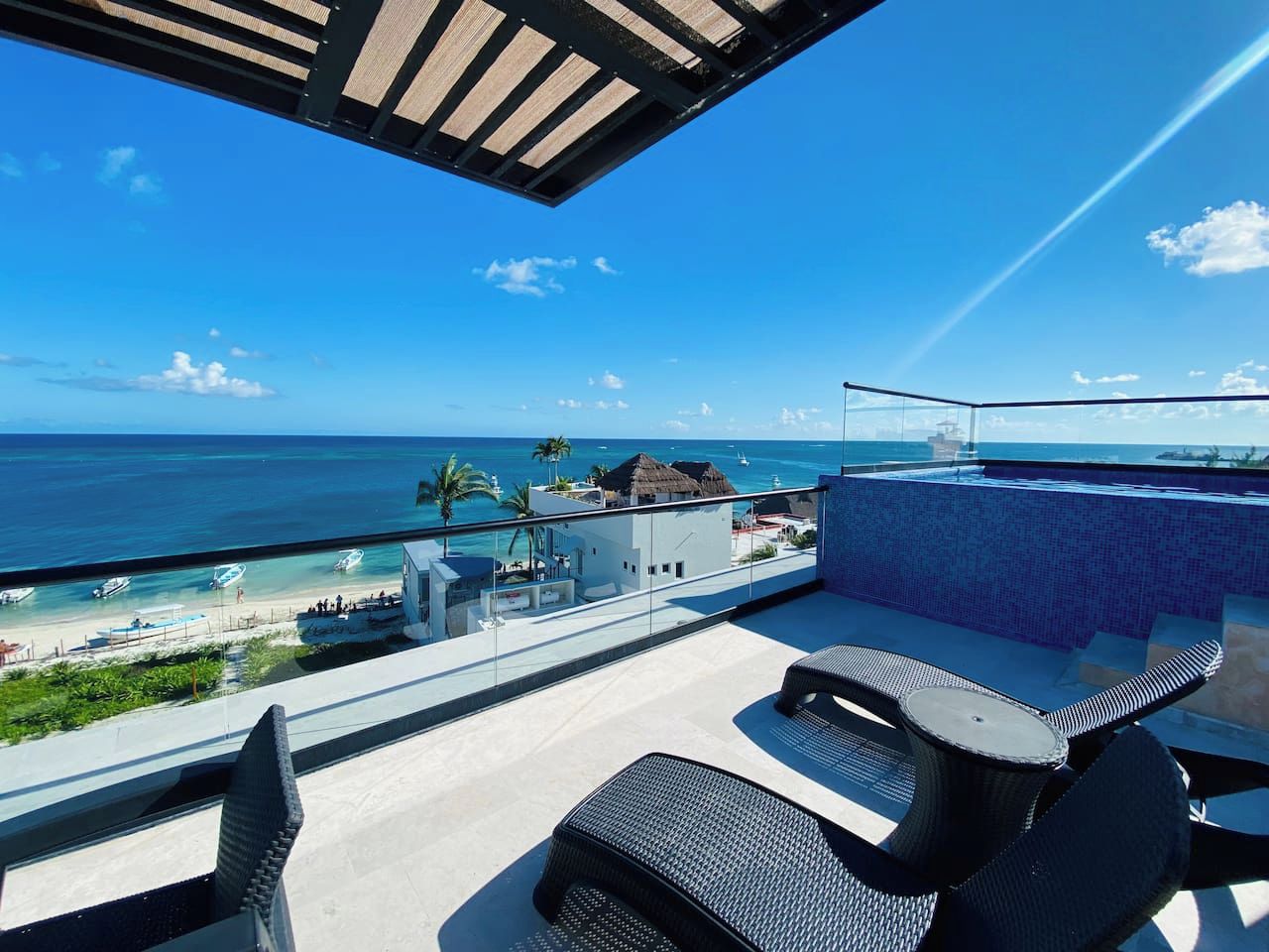 A balcony with a view of the ocean, outdoor seating, and a tiled wall.