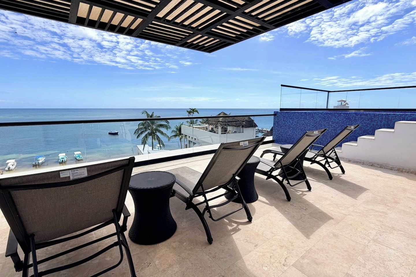 A terrace with outdoor seating and a view of the ocean.