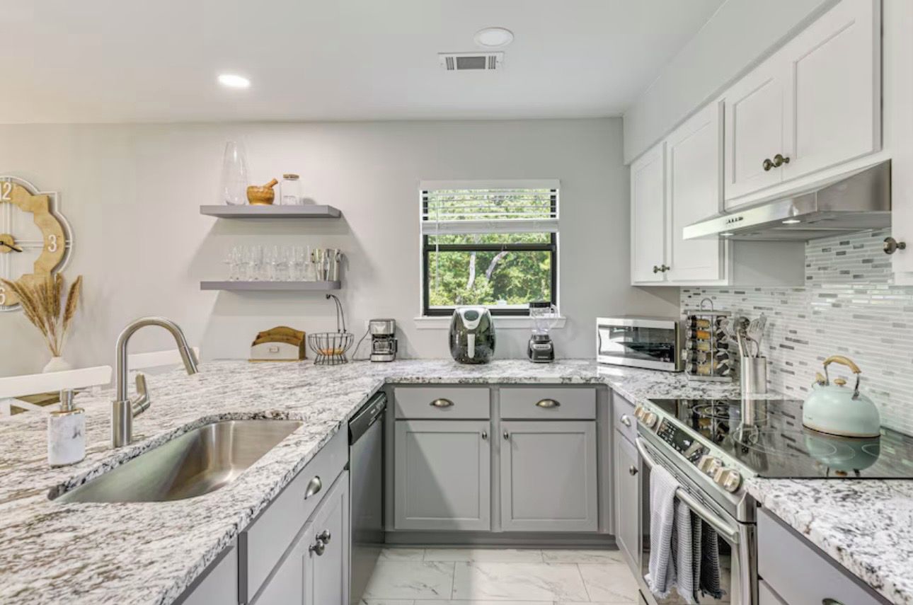 A modern kitchen with granite countertops, stainless steel appliances, and a window providing natural light.