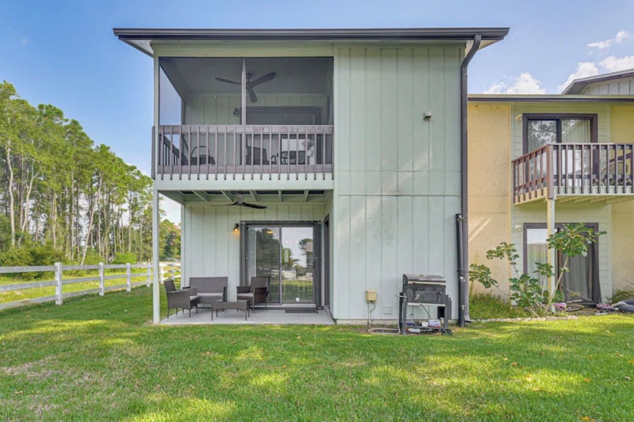 Une maison à deux étages dotée d’un balcon, d’une terrasse avec des sièges et d’un espace barbecue.