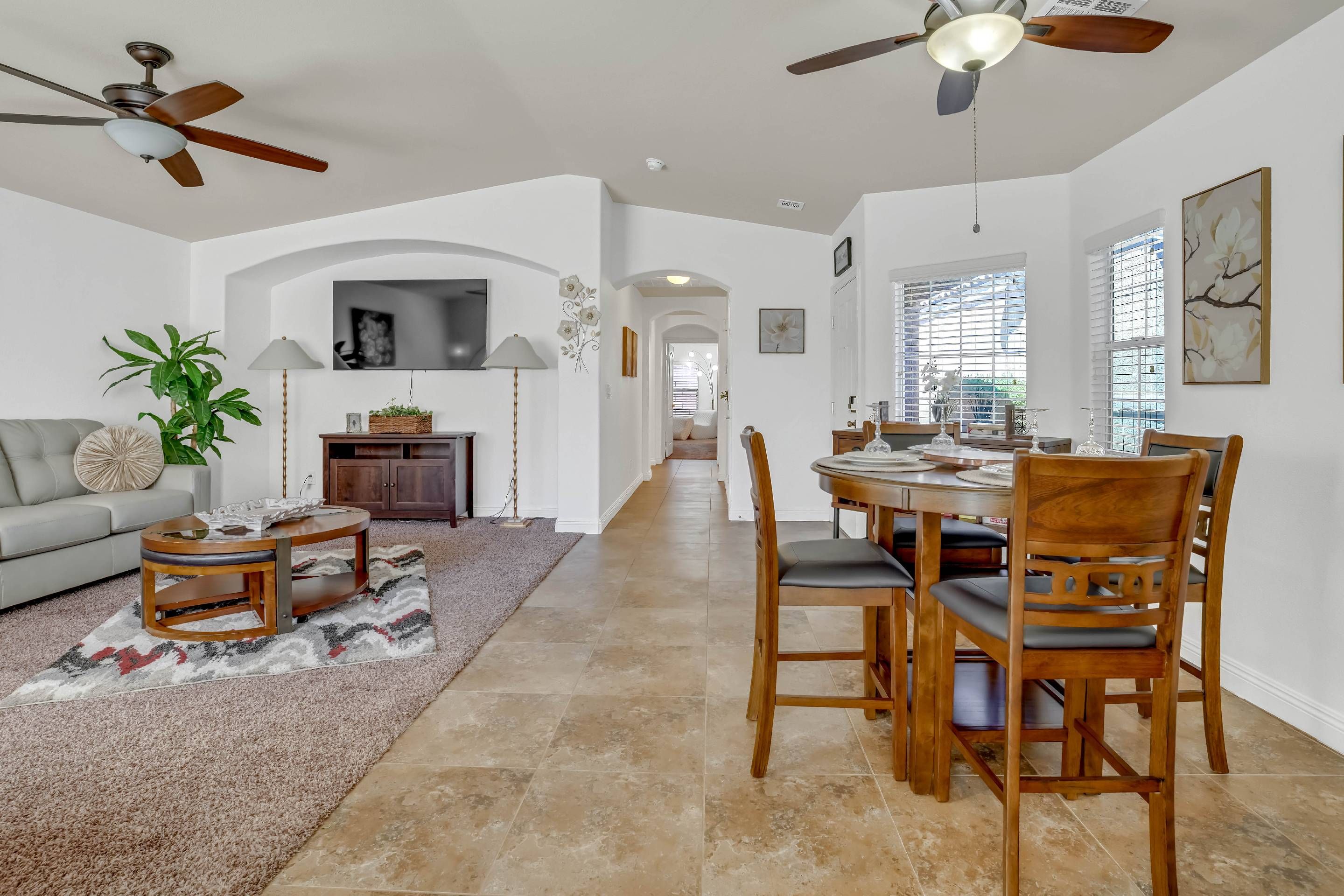 Un salon spacieux comprenant un coin repas, avec un ventilateur de plafond, un canapé, une table basse et une table à manger avec des chaises.