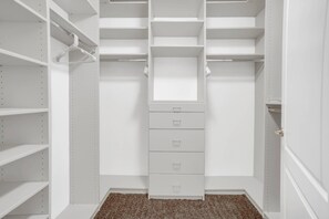 Ein begehbarer Kleiderschrank mit mehreren Regalen, Schubladen und Kleiderstangen.