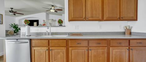 A kitchen with wooden cabinets, a white dishwasher, and a granite countertop.