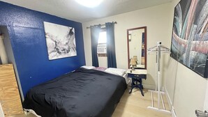 A room with a bed, a desk, a mirror, and artwork on the walls. - Cozy 2-bedroom house in brilliant Dilworth with AC (Dilworth)
