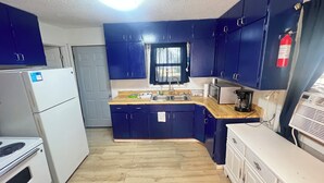 A kitchen with blue cabinets, a white refrigerator, a microwave, and a coffee maker. - Cozy 2-bedroom house in brilliant Dilworth with AC (Dilworth)
