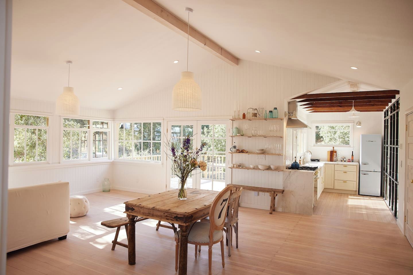 A spacious room with a wooden dining table, chairs, and a vase of flowers.