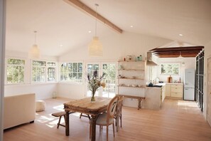 A spacious room with a wooden dining table, chairs, and a vase of flowers. - Sonoma Winemakers Cottage (Sonoma)
