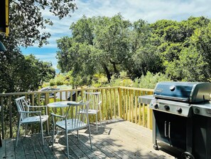 Una terrazza esterna con una griglia barbecue e sedie in metallo.