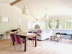 Ein geräumiges Zimmer mit einem Holzessttisch, lila Stühlen, einem weißen Sofa und einem kleinen Couchtisch.