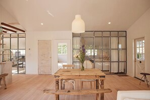 Un'ampia stanza con un tavolo da pranzo in legno, un lampadario e un'ampia finestra con vista.