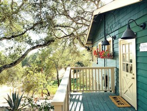 A wooden porch with a mailbox and a door, surrounded by greenery and trees. - Sonoma Winemakers Cottage (Sonoma)
