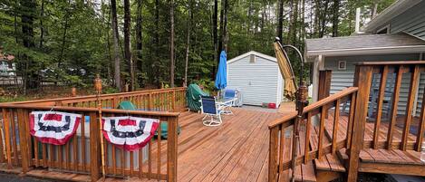 A wooden deck with a railing, a covered seating area, and a small shed.