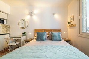 A bedroom with a bed, bedside tables, a desk, a chair, a mirror, and a window. - Chic Urban Home in Providencia (Providencia)