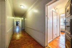 A hallway with wooden flooring, white walls, and a door leading to a room with a bed. - Chic Urban Home in Providencia (Providencia)