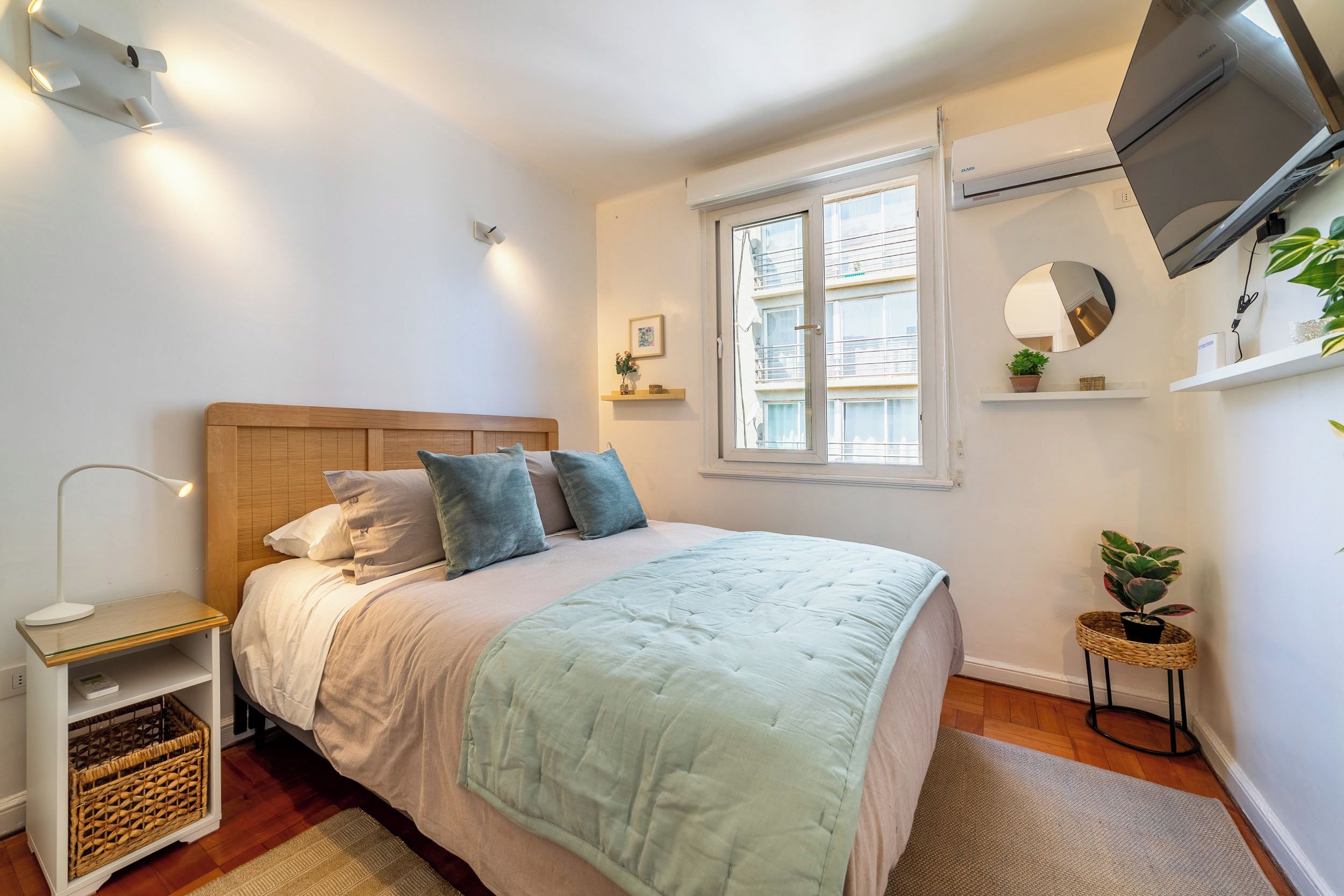 Un dormitorio con cama, mesita de noche, lámpara y una ventana con persianas.