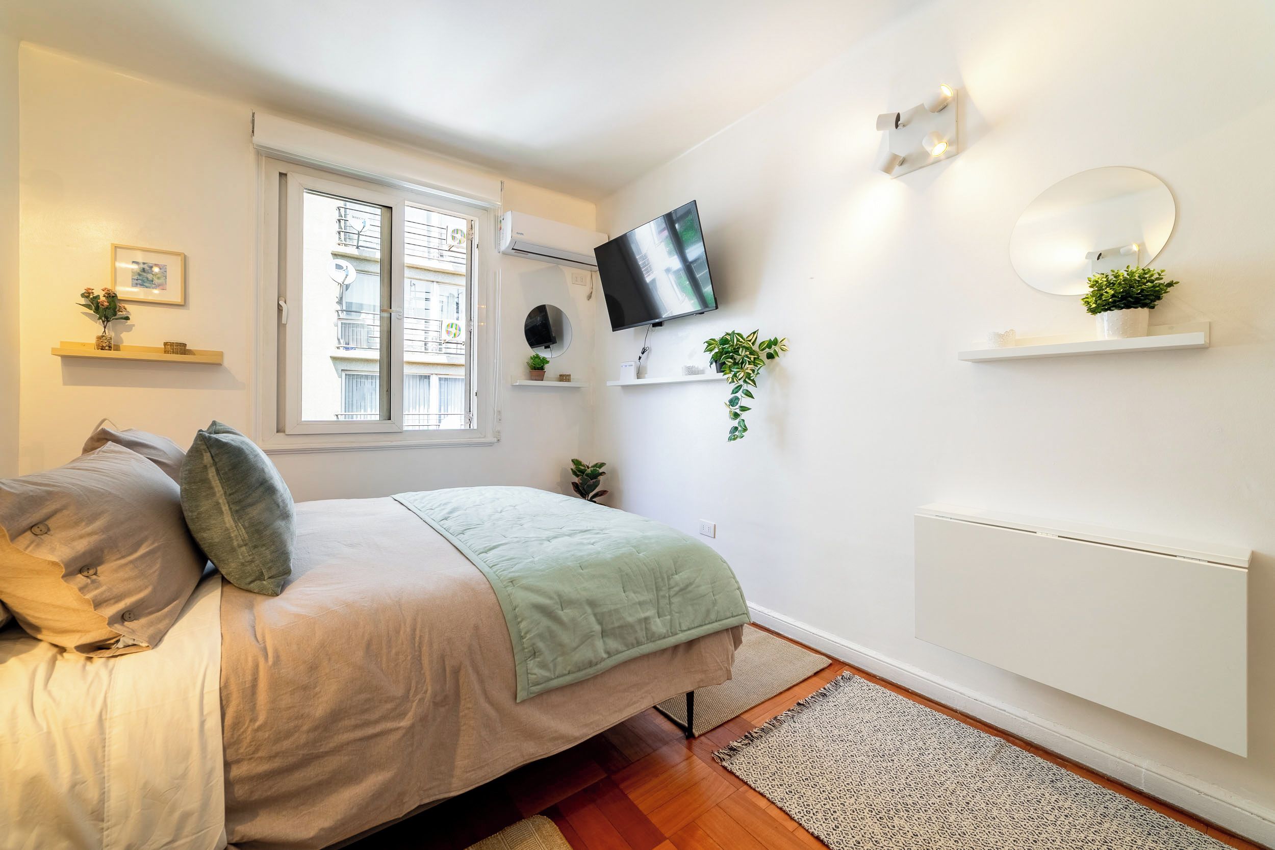 A modern bedroom with a bed, a TV, a window, and a radiator.