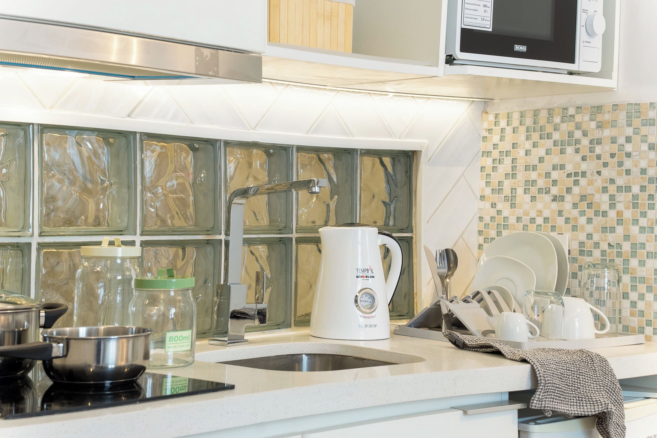 A modern kitchen with stainless steel appliances, a microwave, and a tiled backsplash.