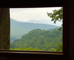 A view through a window of a forested landscape with hills in the distance. - Appalachian Mountain Retreat (Boone)