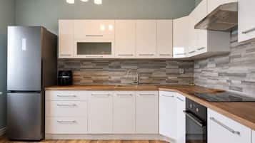 Cocina moderna con armarios blancos, un refrigerador de acero inoxidable, horno empotrado y encimera de madera.