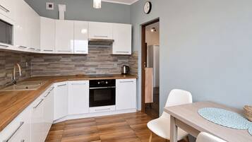 A modern kitchen with white cabinets, a built-in oven, and a wooden countertop.