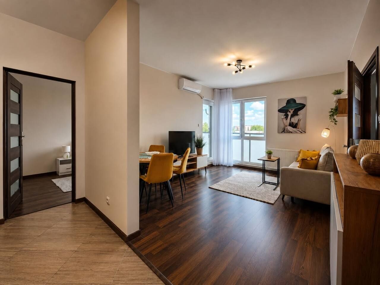 Ein modernes Wohnzimmer mit Essbereich, einer Couch, einem Fernseher und einem großen Fenster.