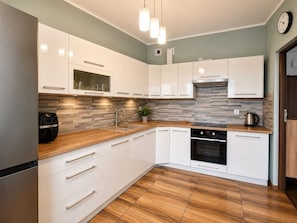 A modern kitchen with white cabinetry, a built-in oven, and a wooden countertop.