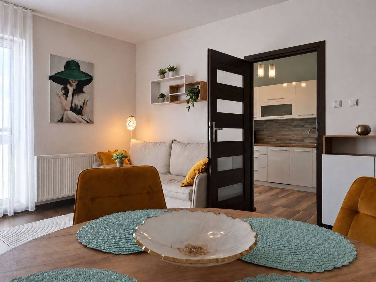 A modern living room with a dining table, chairs, a sofa, and a kitchen visible through an open door.