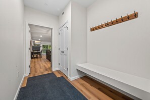 Ein Flur mit Holzboden, dunklem Teppich, Kleiderständer und einer Bank.