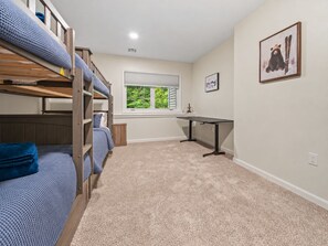 A room with bunk beds, a desk, a window with a view of greenery, and a framed picture on the wall. - New 2026 Build · 3 Min to Loon · Movie Room · Pool & Hot Tub · Sleeps 20 (Lincoln)