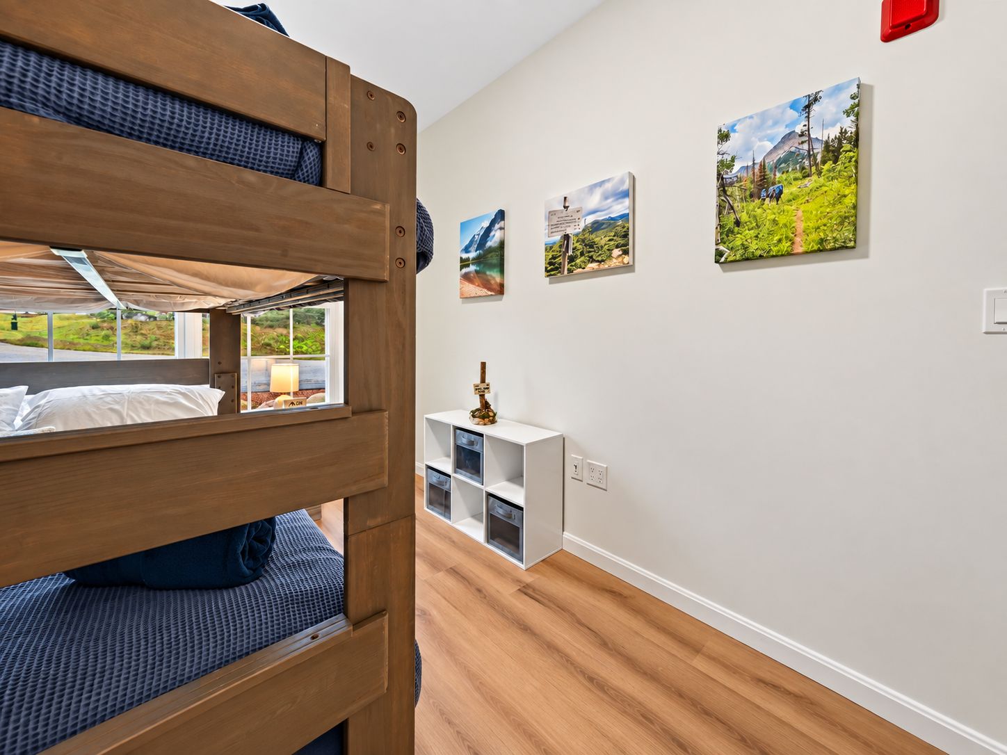 Ein Schlafzimmer mit Etagenbetten, einem weißen Schrank und drei Landschaftsbildern an der Wand.