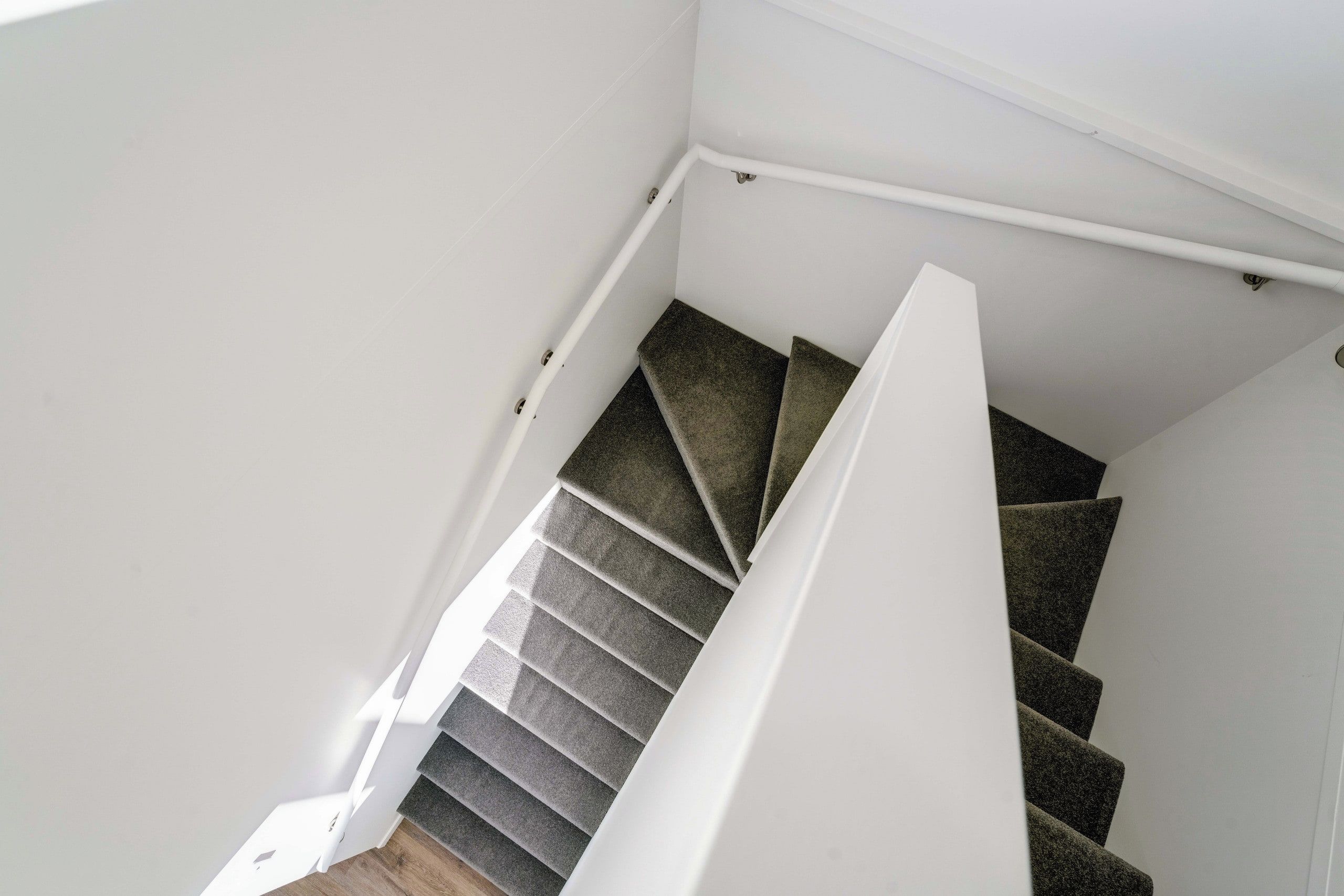 A staircase with carpeted steps and white handrails.