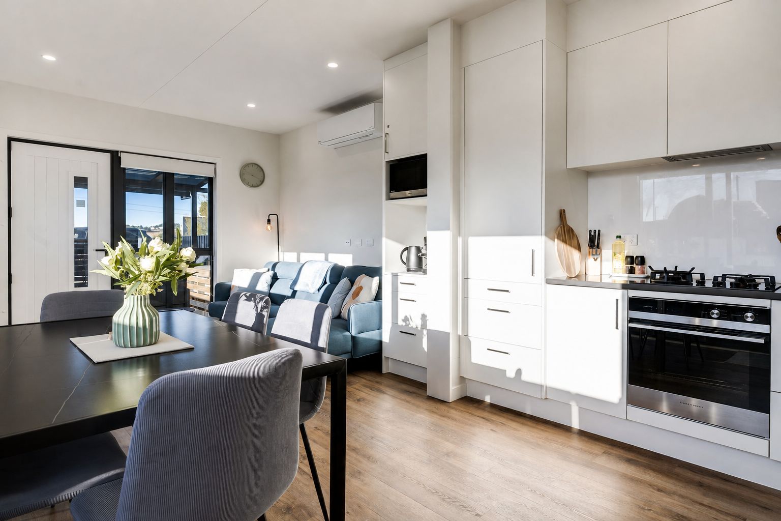 A modern kitchen with white cabinetry, a built-in oven, and a gas stove.