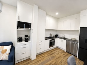 A modern kitchen with white cabinets, a black microwave, a coffee maker, and a stainless steel dishwasher. - Modern & New 3BR - 2.5 bath Haven Near Totara Park (Totara Park)
