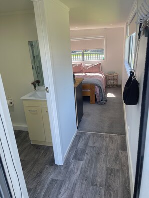 Een slaapkamer met een bed, nachtkastje, een klein rond tafeltje en een raam met uitzicht.