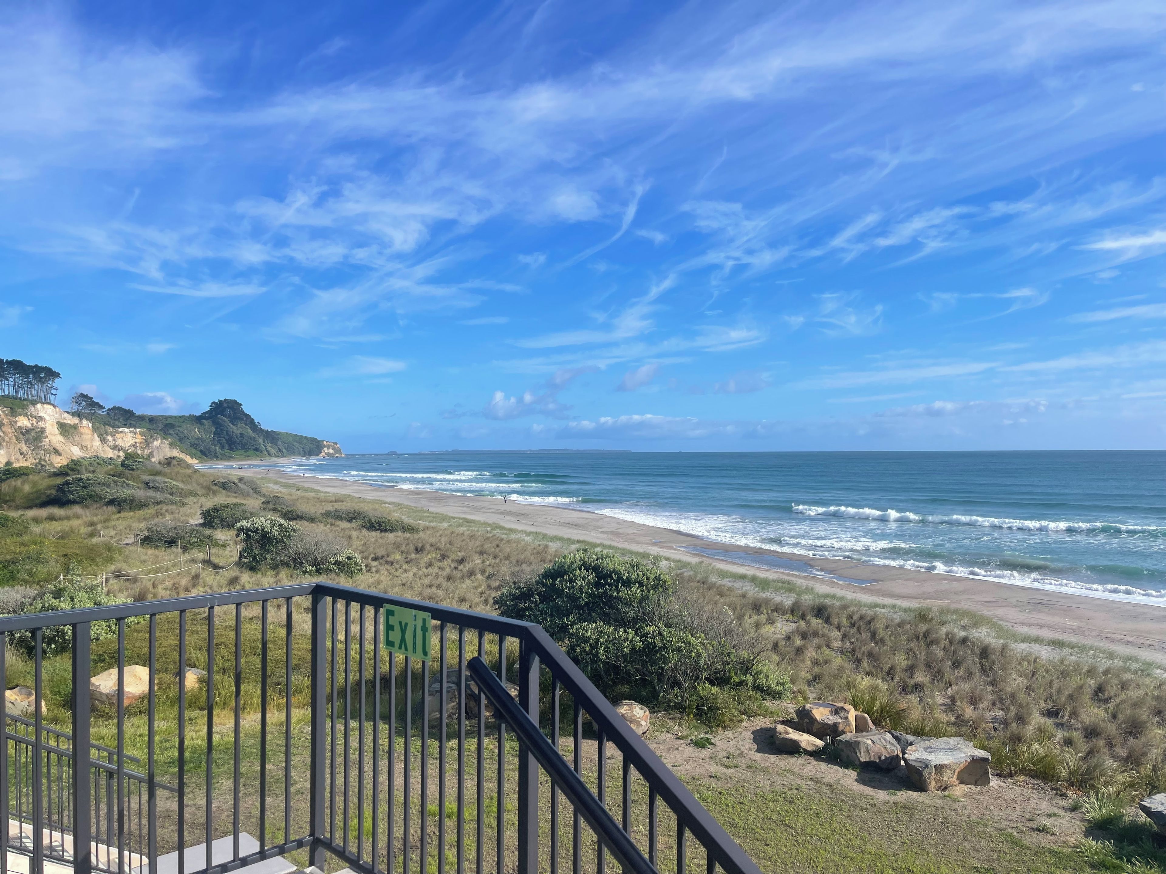 A coastal landscape with a clear sky, a beach, and a staircase leading to an exit.
