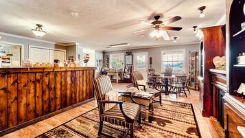 A spacious room with a wooden bar, striped chairs, and a ceiling fan.