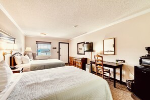Une chambre d’hôtel avec deux lits, un bureau, une télévision et une fenêtre donnant sur un paysage agréable.