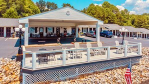 A motel with a covered outdoor seating area, a pool, and a flag. - Deerfield Inn - King Bed w/ Sofa (Hayesville)