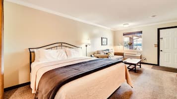 A bedroom with a bed, bedside table, lamp, window, and door.