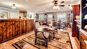 A spacious room with a wooden bar, striped chairs, and a ceiling fan. - Deerfield Inn - King Bed w/ Sofa (Hayesville)