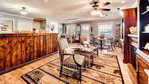 A spacious room with a wooden bar, striped chairs, and a ceiling fan. - Deerfield Inn - Two Queen Beds (Hayesville)