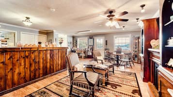A spacious room with a wooden bar, striped chairs, and a ceiling fan.