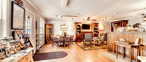 A spacious living room with a dining area, wooden flooring, and a kitchen in the background.
