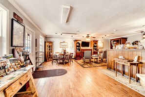A spacious living room with a dining area, wooden flooring, and a kitchen in the background. - Deerfield Inn - Two Queen Beds (Hayesville)